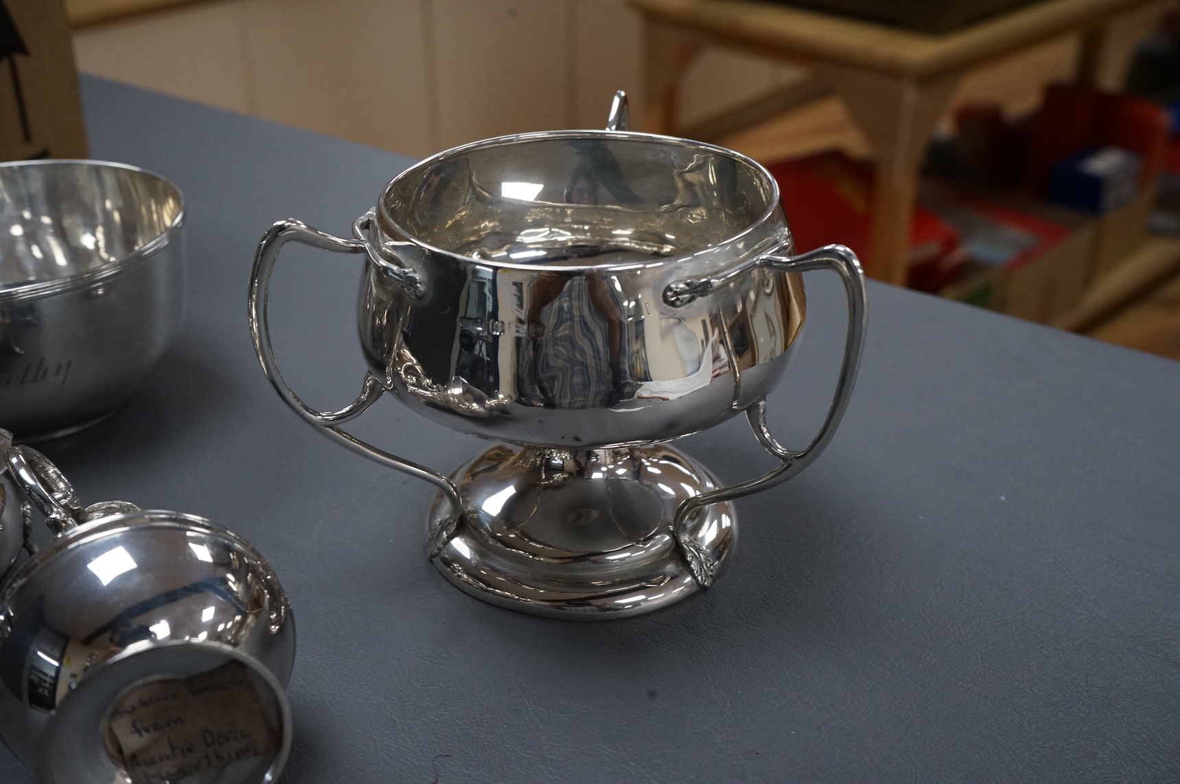 A collection of small silver including an Edwardian Art Nouveau tri-handled pedestal bowl, Birmingham, 1909, height 90mm, a sugar bowl, three cigarette cases, goblet, communion jug, five condiments, three napkin rings, e